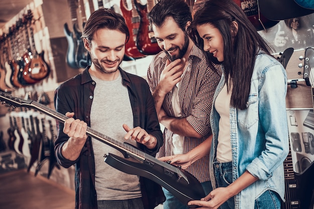 Il venditore di strumenti musicali mostra la chitarra per gli acquirenti.