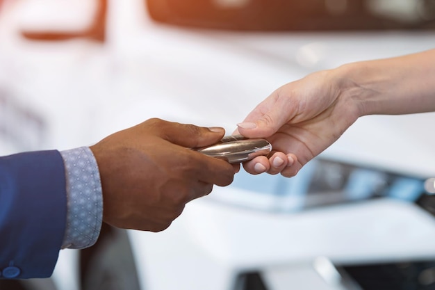 Il venditore e la cliente si stringono la mano e passano la chiave dell'auto