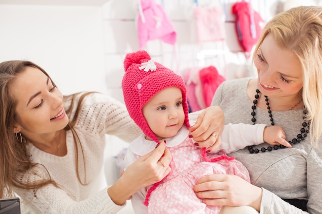 Il venditore mostra alla ragazza un cappello rosa invernale con pompon per selezionare gli acquisti