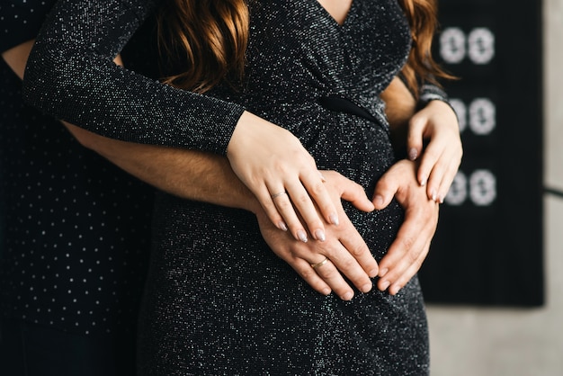 Il ventre delle mani di una ragazza incinta a forma di cuore