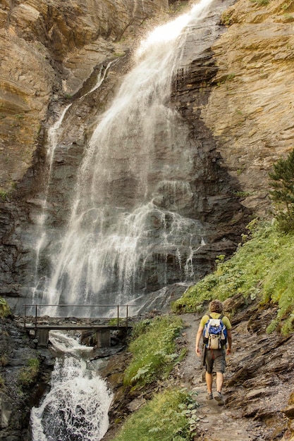 Il viaggiatore cammina verso una cascata con un ponte