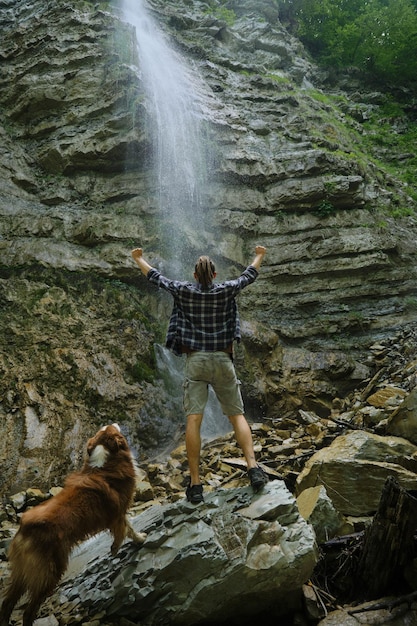 Il viaggiatore caucasico con il cane da pastore australiano gode della natura mentre cammina