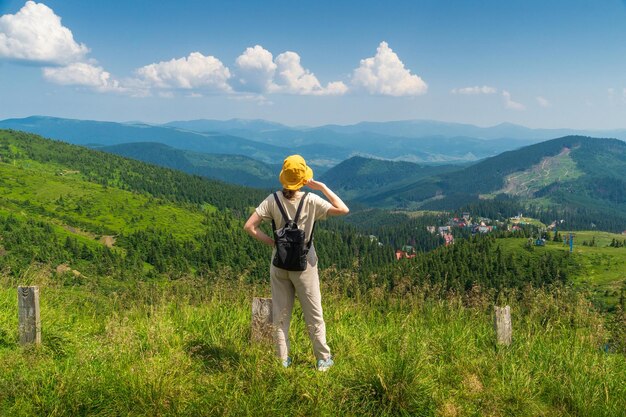 Il viaggiatore con cappello e zaino che riposa nella natura Una ragazza turistica guarda il panorama delle montagne