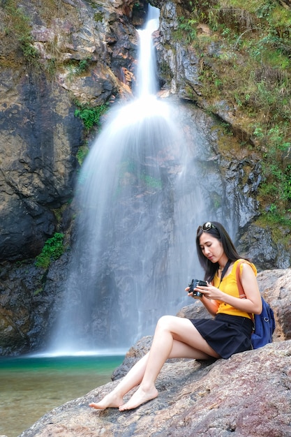 il viaggiatore della donna prende la cascata della foto dalla sua macchina fotografica