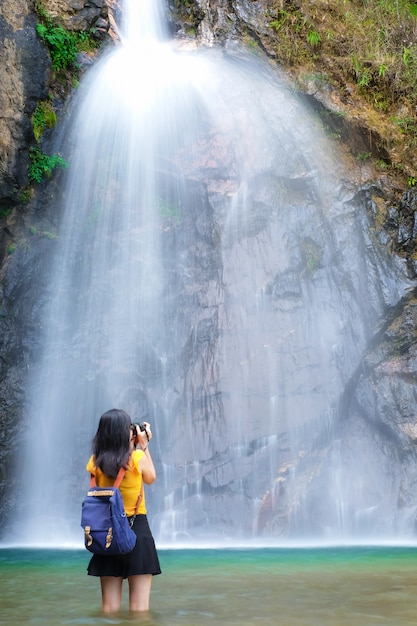 il viaggiatore della donna prende la cascata della foto dalla sua macchina fotografica