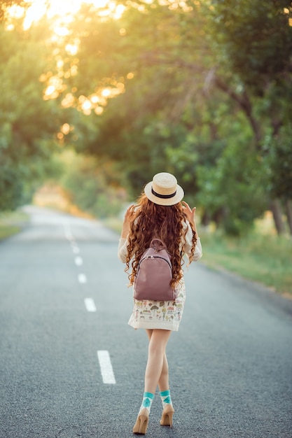 Il viaggiatore della ragazza gode del viaggio. Donna felice che cammina sulla strada.