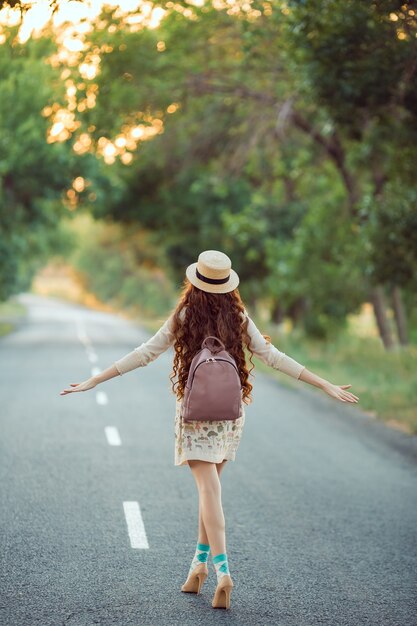 Il viaggiatore della ragazza gode del viaggio. Donna felice che cammina sulla strada.