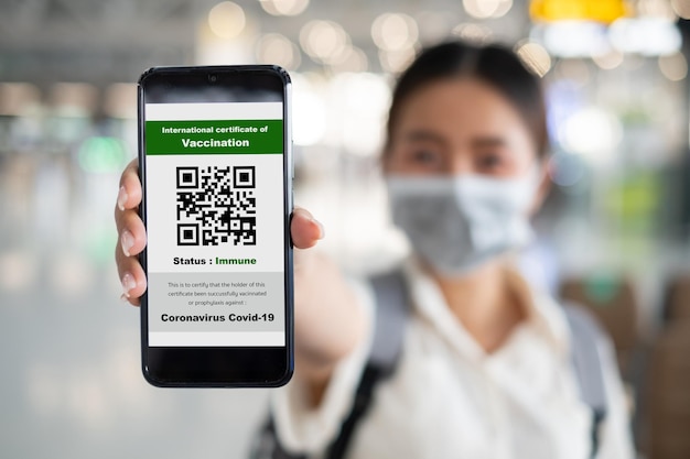 Il viaggiatore mostra il passaporto sanitario della certificazione di vaccinazione al telefono all'aeroporto per certificare che è stato vaccinato contro il coronavirus covid19