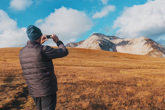 Il viaggiatore turistico fotografa le montagne coperte di nuvole su uno smartphone