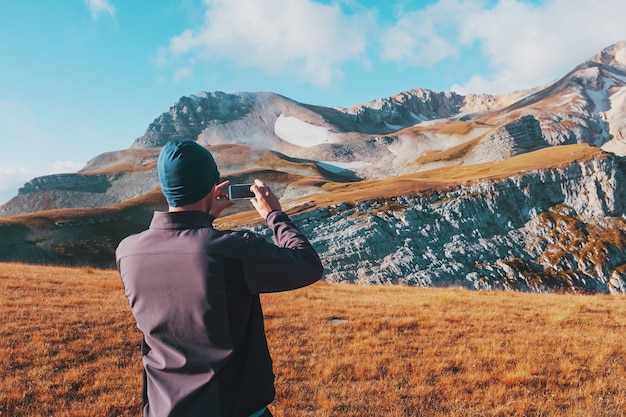 Il viaggiatore turistico fotografa le montagne coperte di nuvole su uno smartphone