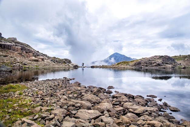 Il viaggiatore va in un paesaggio panoramico con un lago in alta montagna