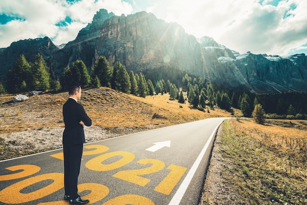 Il viaggio del capodanno 2021 e il concetto di visione futura. Uomo d'affari che viaggia su una strada autostradale che conduce alla celebrazione del felice anno nuovo all'inizio del 2021 per un inizio fresco e di successo.