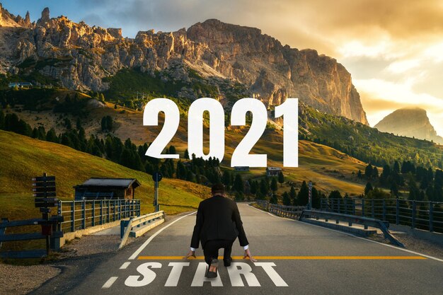 Il viaggio del capodanno 2021 e il concetto di visione futura. Uomo d'affari che viaggia su una strada autostradale che porta alla celebrazione del felice anno nuovo all'inizio del 2021 per un inizio fresco e di successo.