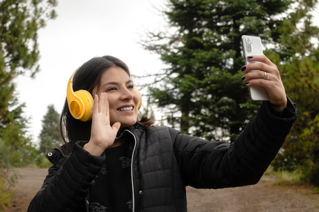 Il video di una giovane donna adulta chiama i suoi amici con il suo smartphone mentre cammina nei boschi