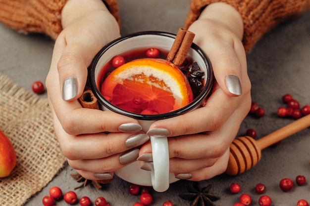 Il vino cotto caldo in mani della donna si chiude in su