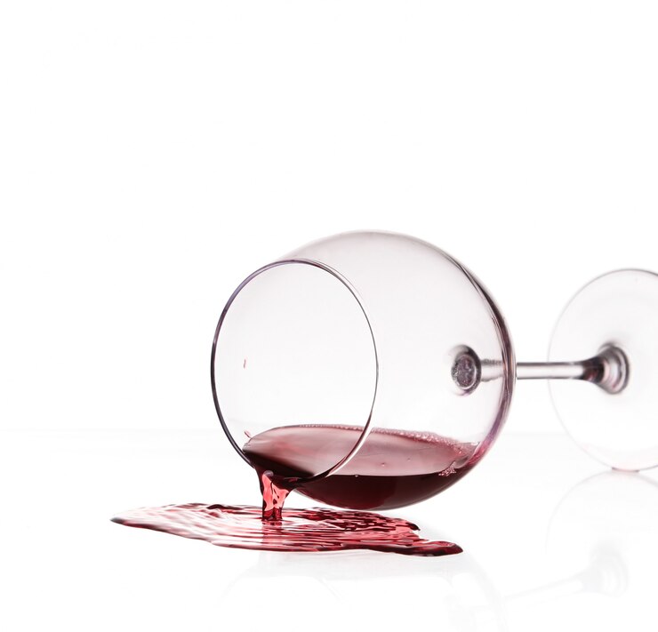 Foto il vino rosso si è rovesciato da vetro sopra fondo bianco