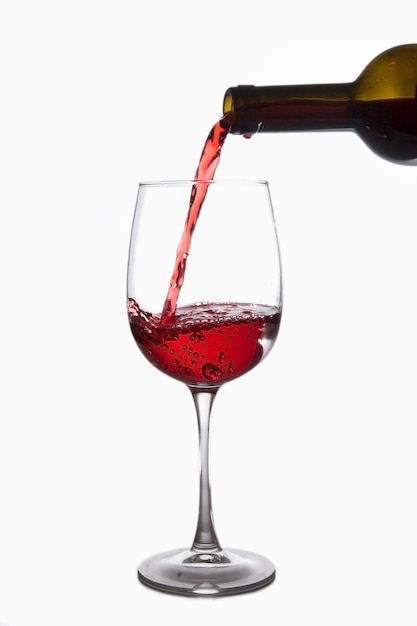 Il vino rosso viene versato in un bicchiere da una bottiglia, isolato su sfondo bianco white