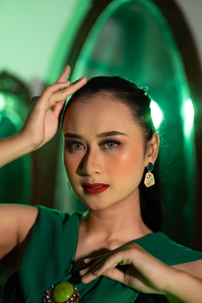 Il viso con un bel trucco e labbra rosse di una donna asiatica in abito verde e gioielli