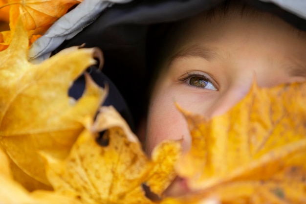 Il viso del bambino è coperto di foglie autunnali