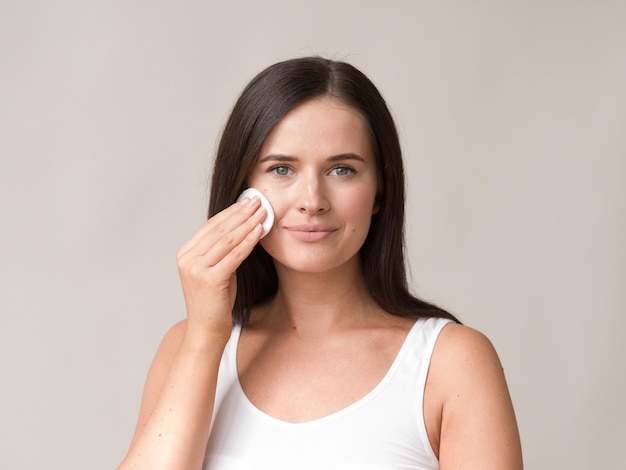 Il viso della donna del batuffolo di cotone rimuove il trucco naturale della pelle sana. Colpo dello studio.