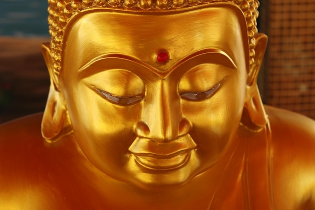 Il viso della statua di Buddha di colore dorato con uno sfondo sfocato