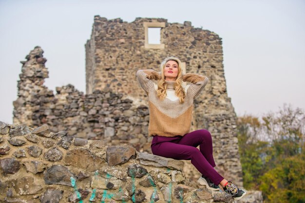 Il viso di trucco della donna si siede su uno sfondo di rovine pietrose sfocato Concetto di turismo Esplora le rovine del castello della metà del secolo Turista alla moda Vacanze e viaggi Agenzia di viaggi Destinazioni di viaggio