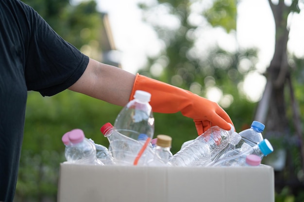 Il volontario asiatico della donna trasporta le bottiglie di plastica dell'acqua nella spazzatura della scatola dell'immondizia nel concetto di ecologia dell'ambiente di riciclaggio dei rifiuti