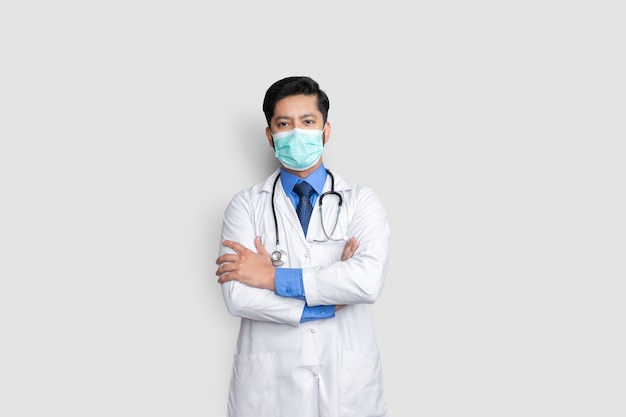 Il volto di giovane medico maschio coperto di maschera e il braccio attraversano il muro isolato, concetto di salute health