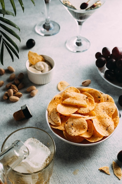 Il whisky viene versato in un bicchiere con ghiaccio, ci sono bicchieri di patatine e altri snack nelle vicinanze