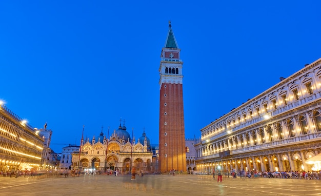 Illuminata Piazza San Marco con il Campanile e la Basilica di Venezia al tramonto, Italia. Luoghi d'interesse, paesaggio urbano veneziano