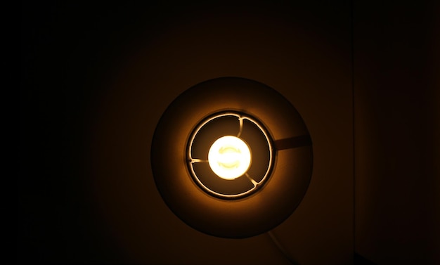 Illuminazione della lampadina economica nella lampada da tavolo nelle tenebre vista dall'alto
