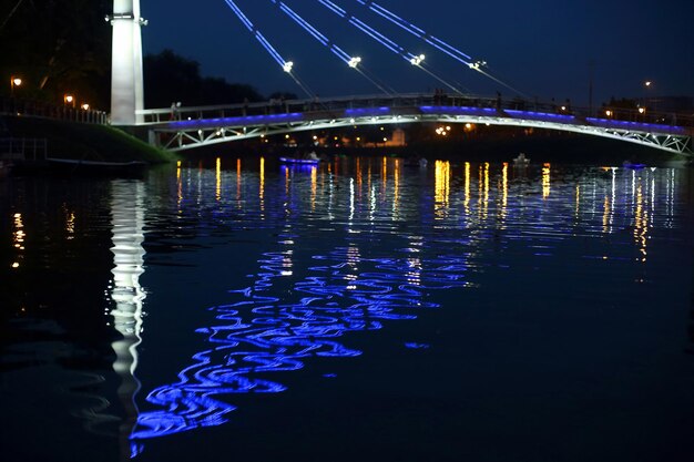 Illuminazione notturna riflessa del ponte sul fiume