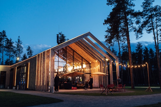 Illuminazione serale nel cortile con lo sfondo di una moderna casa in legno