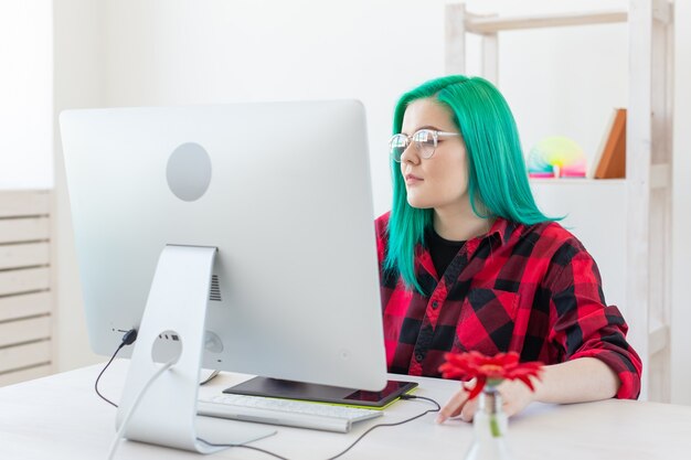 Illustrator, graphic designer, animatore e artista concept - creatore donna con bellissimi capelli verdi e occhiali che disegnano nel laptop