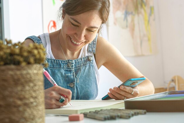 Illustrator lavora con un grande sorriso sul viso mentre consulta il suo cellulare per trovare ispirazione