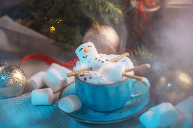 Illustrazione invernale con una tazza di cioccolata calda in cui giace un uomo marshmallow sorridente, tutto questo in decorazioni natalizie