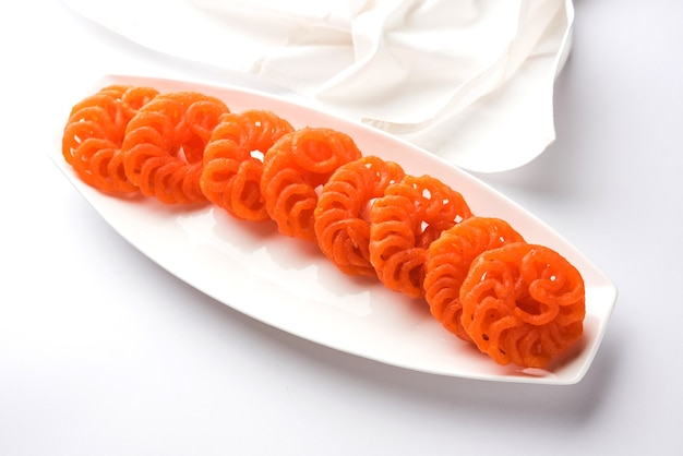 Imarti o Jalebi dolci indiani serviti in un piatto di ceramica bianca su sfondo bianco