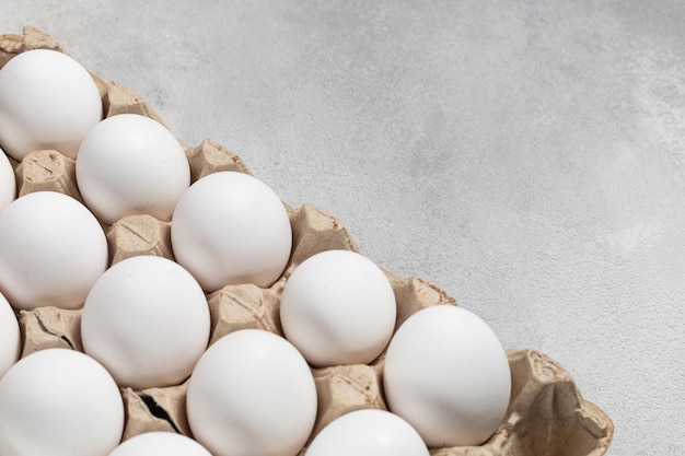 Imballaggio di uova di gallina bianche su sfondo grigio