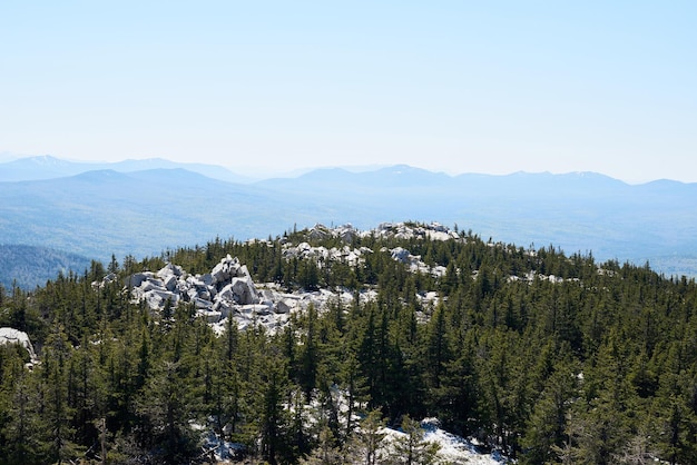 Immagine aerea di massicce rocce bianche circondate da boschi di conifere e alte montagne in lontananza o