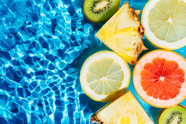 Immagine astratta colorata di frutta agrumi limone kiwi arancia ananas pompelmo limone pomelo in acqua Piatto lay