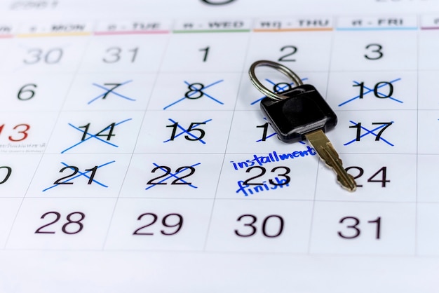 Immagine chiusa della chiave dell'auto sul calendario bianco con segnata una data per contrassegnare il promemoria dell'appuntamento dei pagamenti rateali per il finanziamento dell'auto.