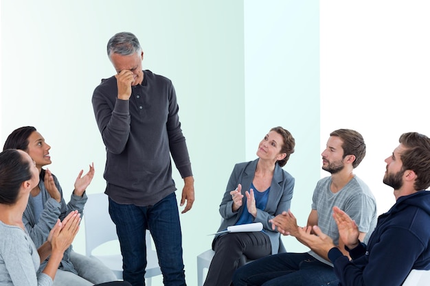 Immagine composita del gruppo di riabilitazione che applaude felice l'uomo in piedi