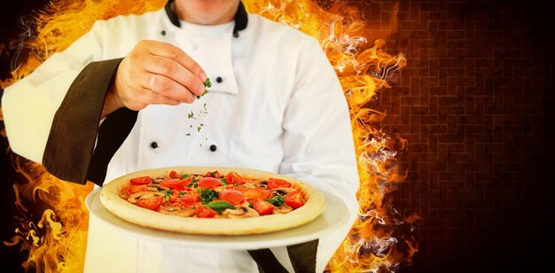 Immagine composita del ritratto di uno chef in possesso di una pizza e l'aggiunta di erbe aromatiche