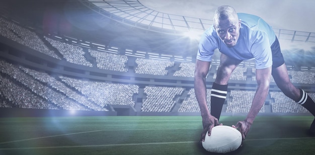 Immagine composita del ritratto di uno sportivo che si piega e tiene la palla mentre gioca a rugby con