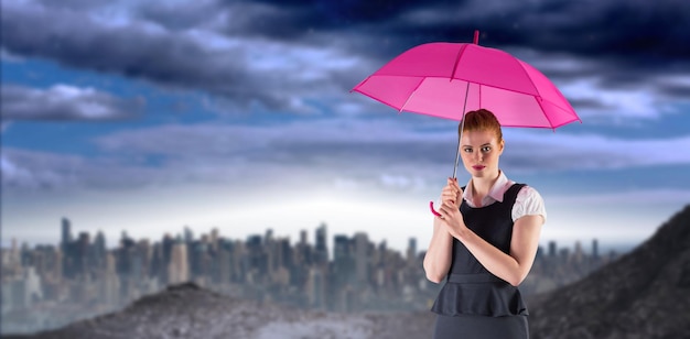 Immagine composita dell'ombrello della holding della donna di affari della testarossa graziosa