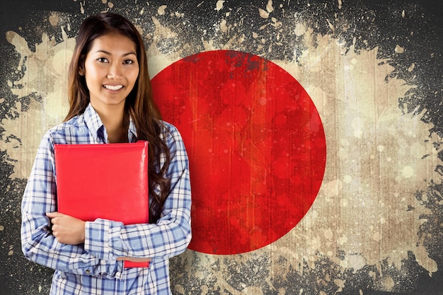 Immagine composita della donna asiatica sorridente che tiene libro rosso