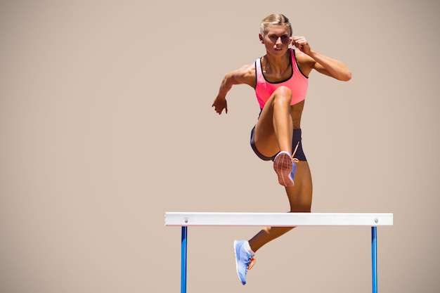 Immagine composita della donna atletica che pratica il salto ostacoli