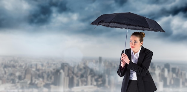 Immagine composita della donna di affari che tiene un ombrello nero