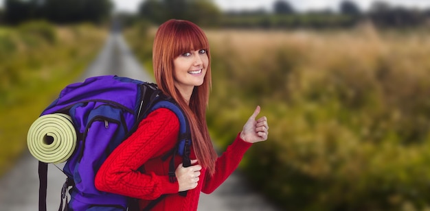 Immagine composita della donna sorridente dei pantaloni a vita bassa con una borsa da viaggio