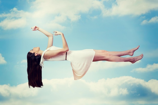 Immagine composita della ragazza in vestito bianco che galleggia nell'aria